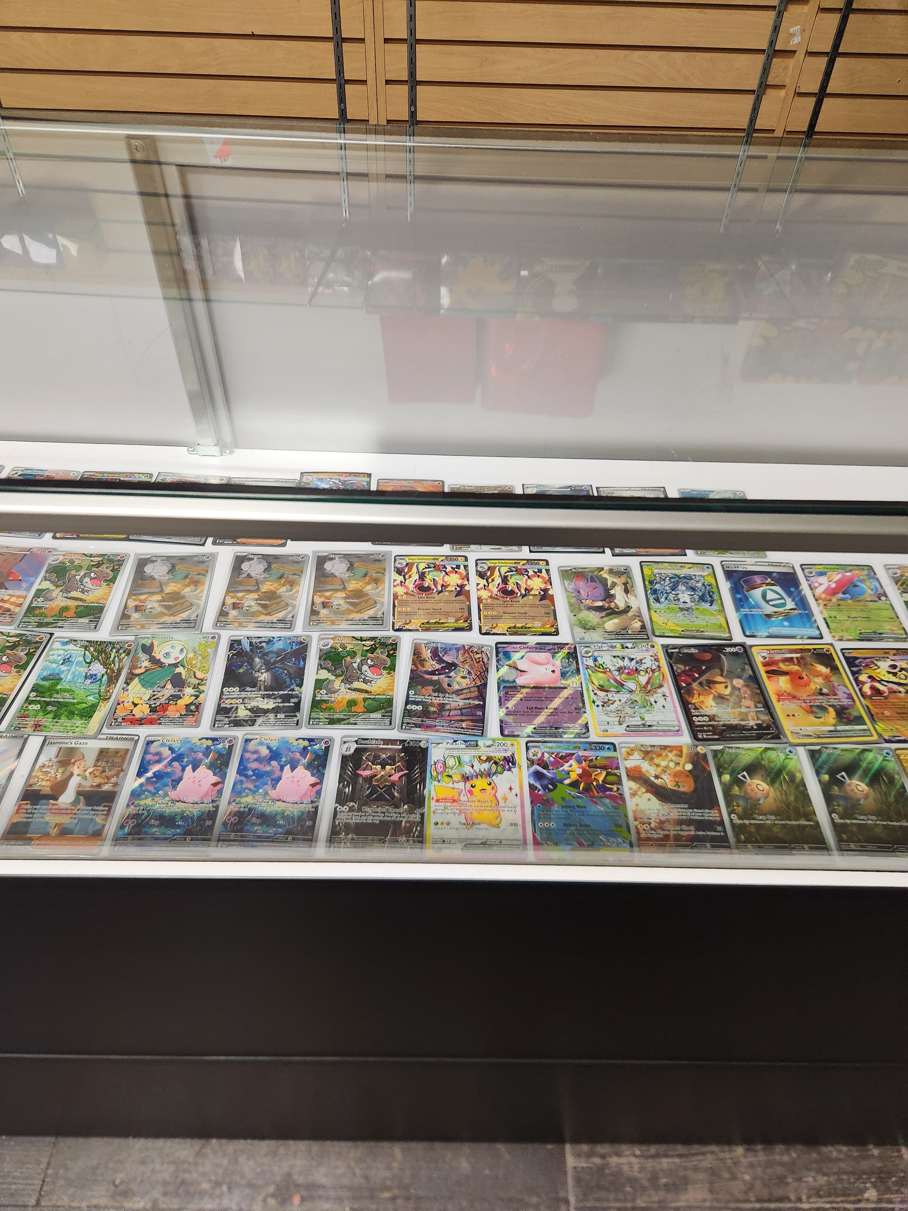 Pokemon singles display case at The Wolf Den with organized card inventory